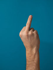 Middle finger, offensive gesture. Fuck you concept. Blue background