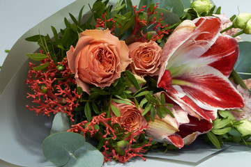 Fototapeta na wymiar Romantic wedding or congratulatory bouquet of roses, hippeastrum, jatropha and eucalyptus, light gray background, selective focus