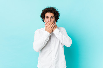 Fototapeta na wymiar Young curly mature man wearing an elegant shirt shocked covering mouth with hands.