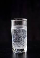 A glass of state-of-the-art water in a high glass on a black background. Drinking balance.