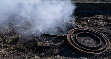 Steam, smoke, and gas flow from the open hatch on the street.
