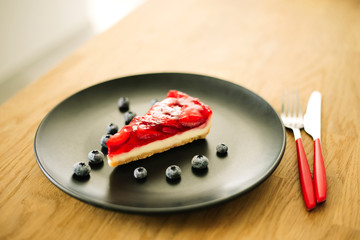 Strawberry cheesecake with blueberries on black plate
