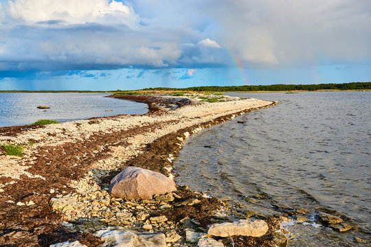Beautiful sunset with a rainbow on the coast of the sea with a rocky shore