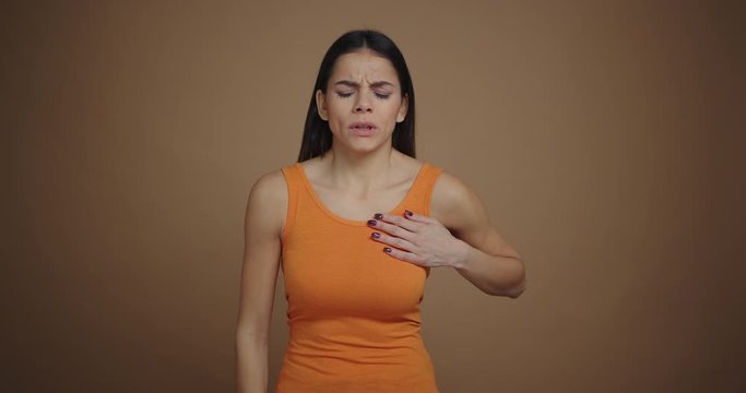 Young woman having a heart attack isolated on brown background