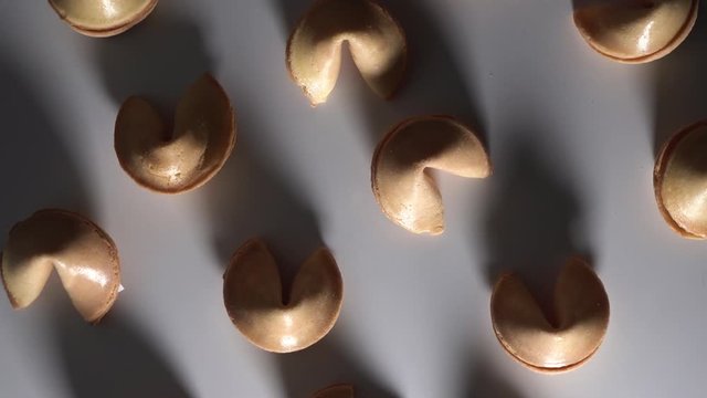 Low key light. Top down view of Chinese cookies rotate on a white background. Traditional fortune cookie. Nice view on spinning biscuit crispy sweet cookie. shadow dance