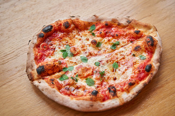 Pizza Margarita. Baked tasty margherita pizza in Traditional wood oven in Neapolitan restaurant, Italy.