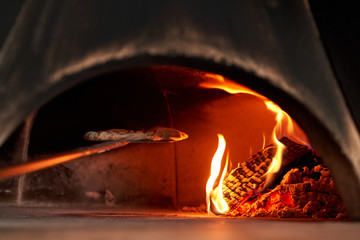 Fototapeta premium Baked tasty margherita pizza in Traditional wood oven in Naples restaurant, Italy. Original neapolitan pizza. Red hot coal.
