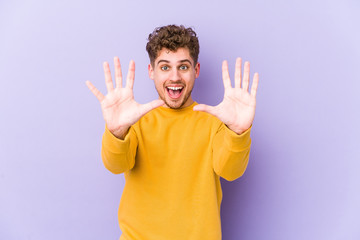 Young blond curly hair caucasian man isolated showing number ten with hands.