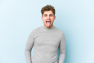 Fototapeta premium Young blond curly hair caucasian man isolated funny and friendly sticking out tongue.