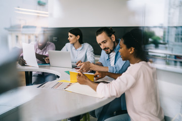 Multiethnic workgroup of young employees developing strategy at meeting in office