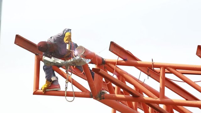 The welding workers at structures site. Worker is welding steel structures. Workers are also working at high altitude with a set of fall protection devices.