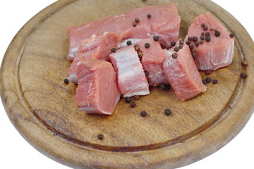 Fresh raw beef meat slices on a round wooden board isolated over white background