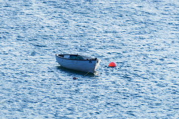 Kleines weißes Boot, an einer roten Boje befestigt in Olshoremore, Schottland