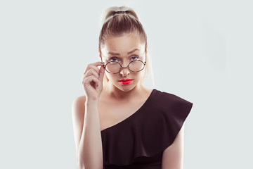 Skeptical suspicious young woman holding eye glasses down looking at you camera isolated on white light blue wall background