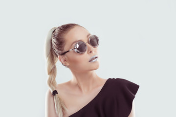 Look at my style, I am all metallic shiny. Woman shows gray metallic mirror lips lipstick in set combination with grey eye glasses, blonde dark hair ombre isolated on White light blue with copy space