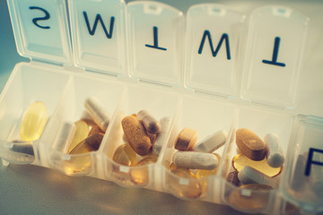 Fototapeta na wymiar Daily pill organizer with drugs, tablets and dietary supplements. Pill box with medication, close up