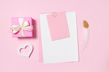 Empty template for romantic letters on a pink background. White feather with gold plating. Real photo, flat lay. Copy space for text.