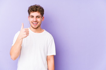 Young blond curly hair caucasian man isolated smiling and raising thumb up