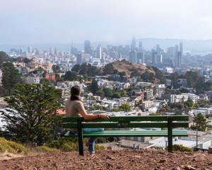 Woman sitting on bench overlooking San Francisco Skyline