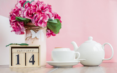Happy Valentine's Day. Wooden calendar for February 14 with flowers a white cup.