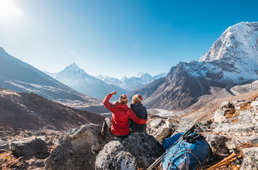 Jeune couple se réjouissant de l& 39 itinéraire de trekking du camp de base de l& 39 Everest près de Dughla 4620m. Les routards ont laissé des sacs à dos et des bâtons de randonnée et profitant de la vue sur la vallée avec le pic Ama Dablam 6812m et le To