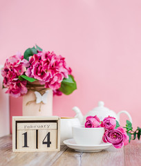 Happy Valentine's Day. Wooden calendar for February 14 with flowers a white cup.