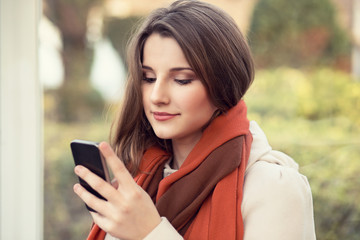 Texting, reading sms. Closeup portrait head shot beautiful young woman girl student looking on mobile phone looking isolated city scape outdoor background. Multicultural mixed race asian russian model