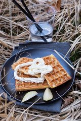 Wafers with cream on a black plate on a background of natural grass.