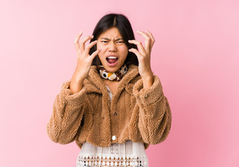 Young asian woman upset screaming with tense hands.