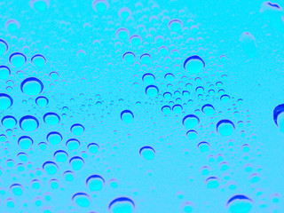 a macro texture photo of water drops on glass tinted blue