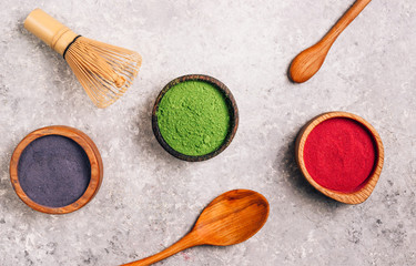Different colors of japanese matcha tea: green, red and blue in wooden bowls on gray background....