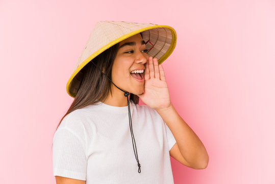 Young asian woman wearing a vietnamese hat isolated Young asian woman wearing a vietnamin hatshouting and holding palm near opened mouth.