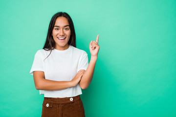 Young mixed race indian woman isolated smiling cheerfully pointing with forefinger away.