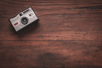 Old and worn photo camera from the 60s on rustic wooden table