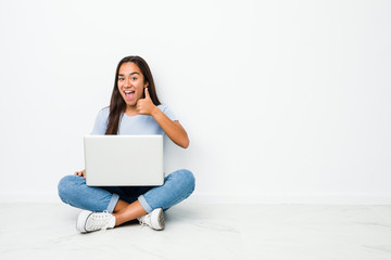 Young mixed race indian woman sitting working on laptop smiling and raising thumb up
