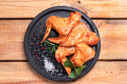 Raw marinated chicken wings for grill and bbq.Raw chicken wings in a marinade with spices on a black plate. Top view. Chicken meat close-up.