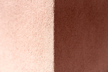 Empty background. Orange wall, porous texture. Corner of the house. One half is illuminated by the sunlight, the other half is in the shade.