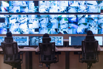 Security guard monitoring modern CCTV cameras in a surveillance room. Group of security guards sitting and monitoring.