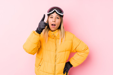 Young caucasian woman wearing a ski clothes in a pink background having an idea, inspiration concept.