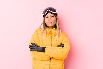 Young caucasian woman wearing a ski clothes in a pink background tired of a repetitive task.