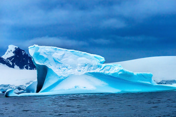 Fototapeta premium Floating Blue Iceberg Snow Glaciers Mountains Charlotte Harbor Antarctica