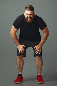 Sportswear concept. Full length portrait of sweet smiling charismatic muscular 30-year-old man with red hair posing over light gray background. Perfect haircut. Studio shot