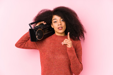 Obraz premium Young afro woman holding a cassete isolated having some great idea, concept of creativity.