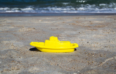 Fototapeta na wymiar Yellow toy boat on the beach