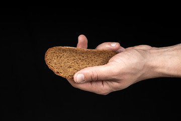 Man holds a piece of bread in his hand on black background
