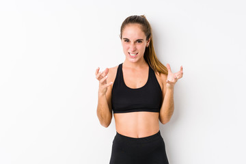 Fototapeta na wymiar Young caucasian fitness woman posing in a white background upset screaming with tense hands.