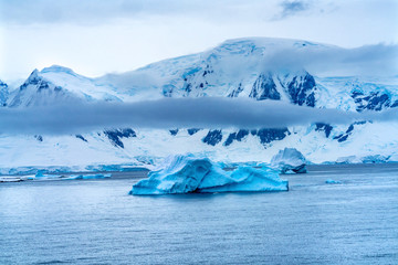 Fototapeta na wymiar Floating Blue Iceberg Snow Glaciers Mountains Charlotte Harbor Antarctica