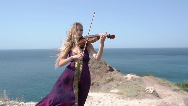 Young adult violinist girl playing classical symphony music on violin