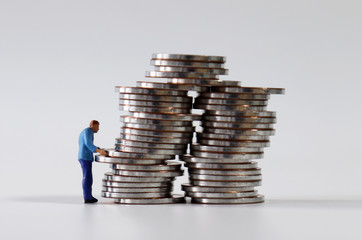 Miniature people and piles of coins. 