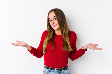Young caucasian woman posing isolated  doubting and shrugging shoulders in questioning gesture.